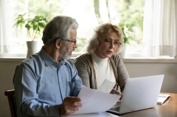 Man and woman sitting in front of a computer looking at paperwork