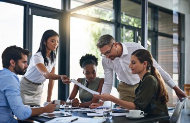 Employees working together around table, sitting, standing