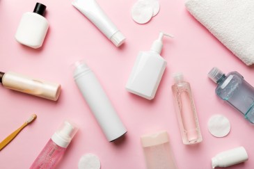 Skincare products laid out on a soft pink background.