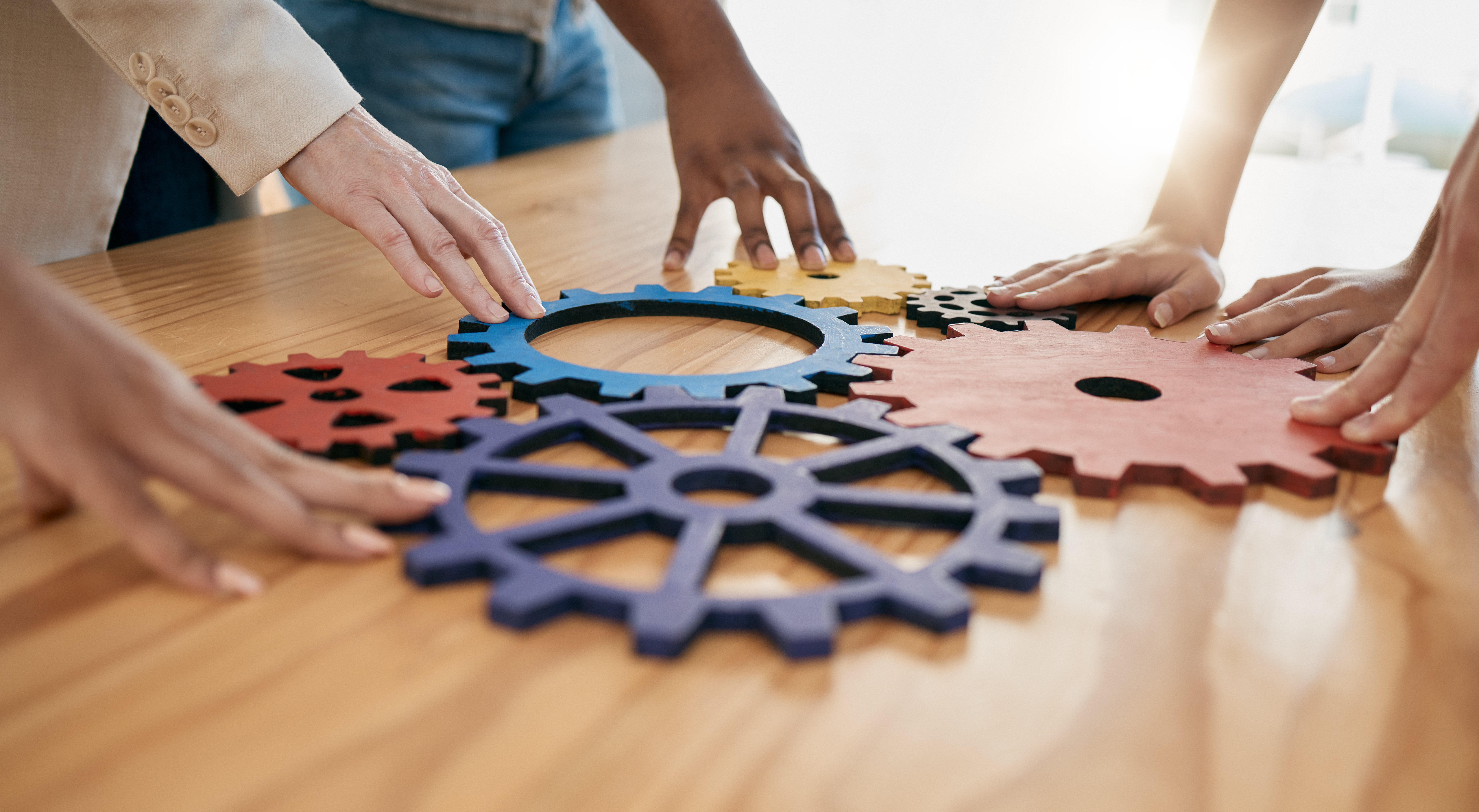 Different gear shapes fit together with diverse hands touching each