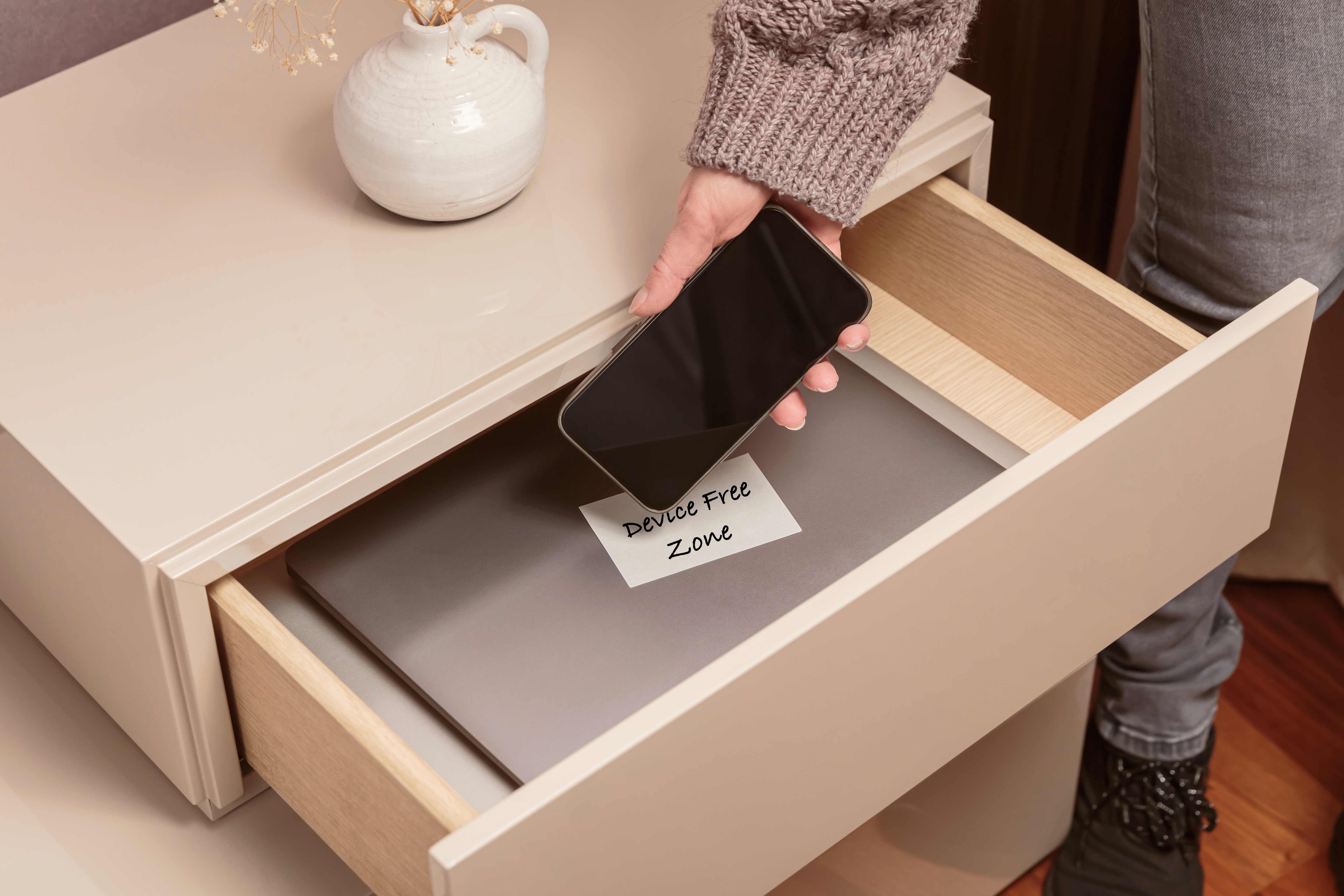 Person putting cell phone in drawer