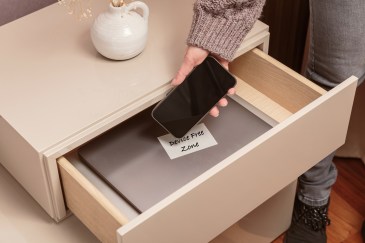 Person putting cell phone in drawer