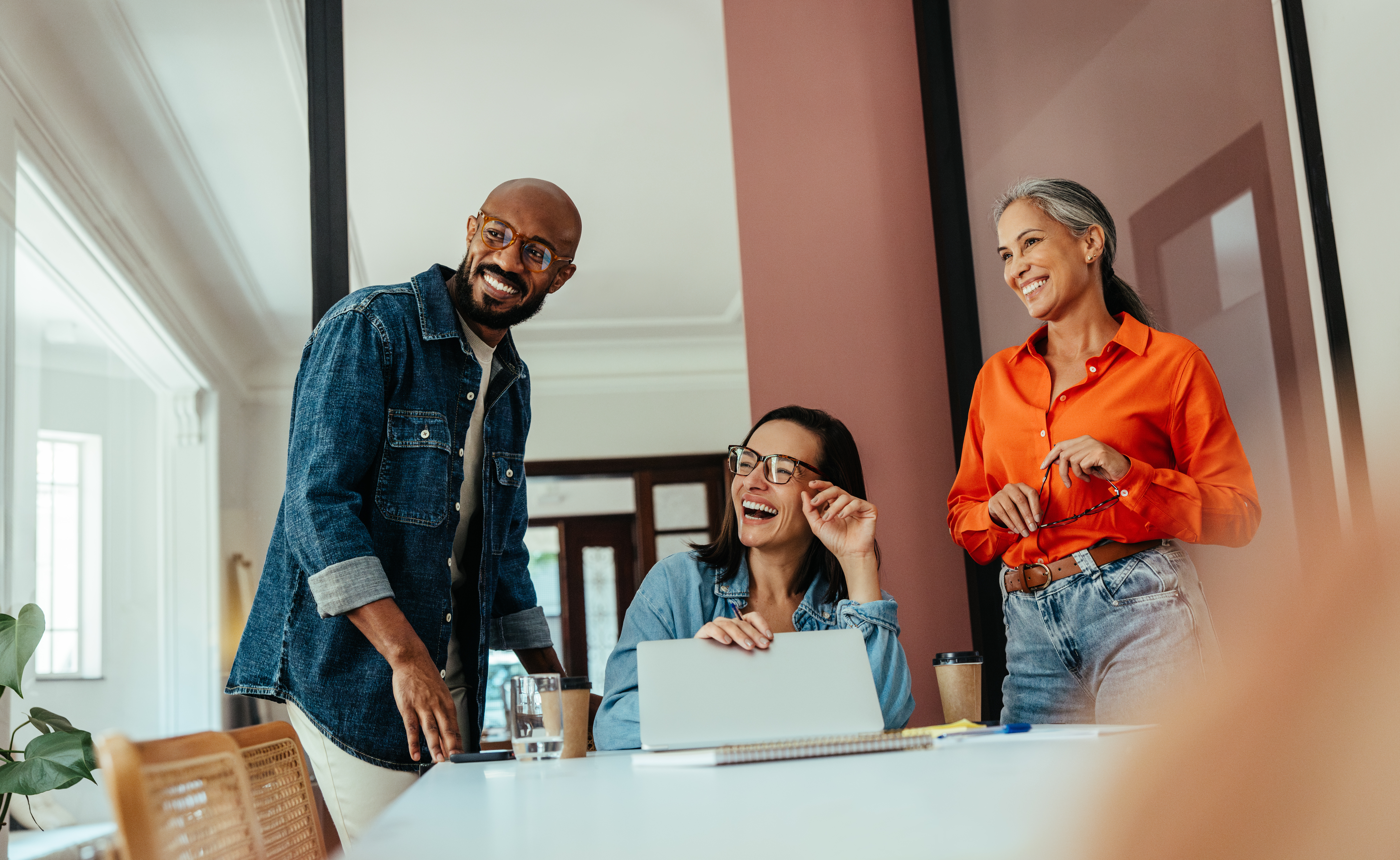Three people in conference room, smiling