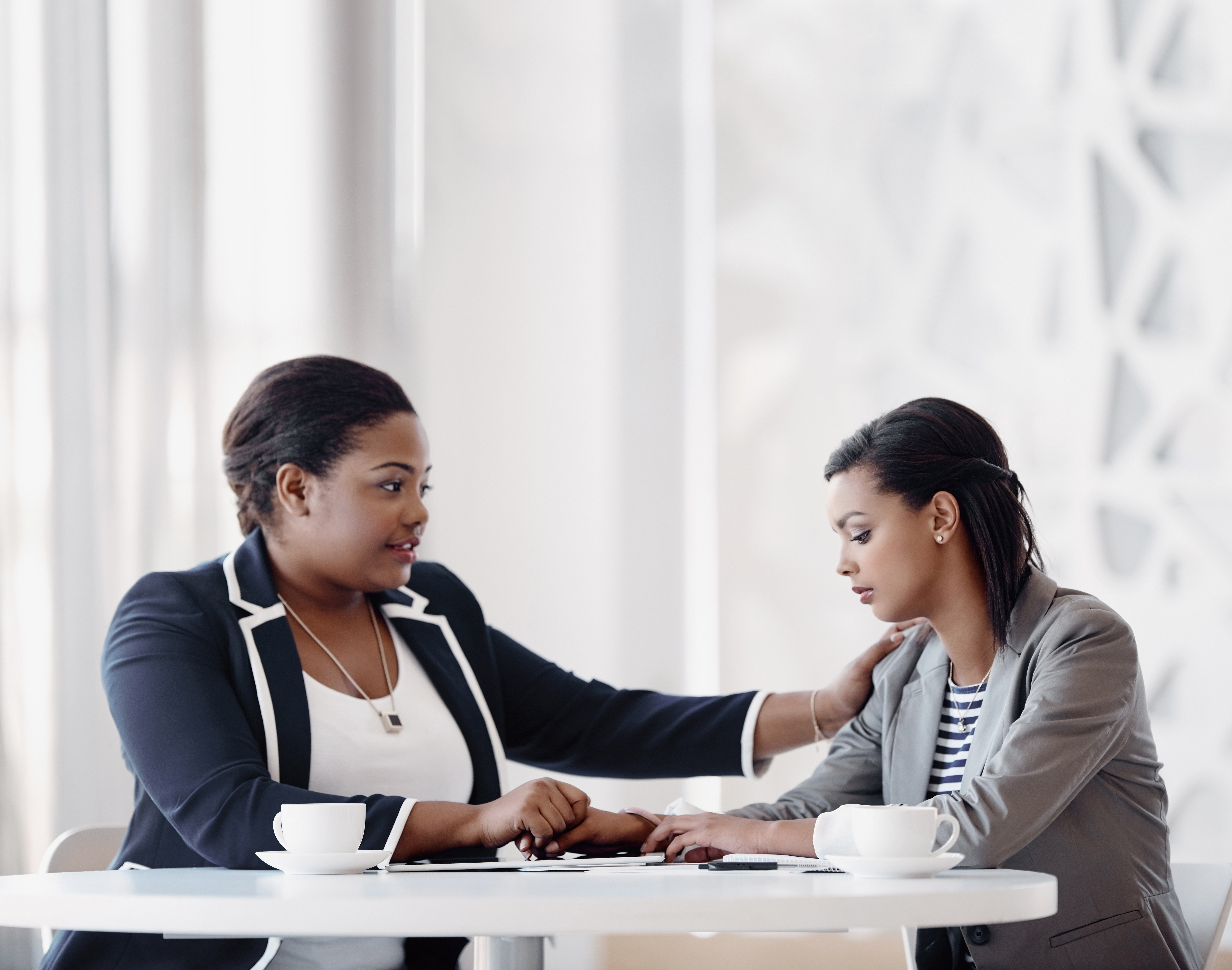 Two female employees, one holding other's hand, showing care and compassion