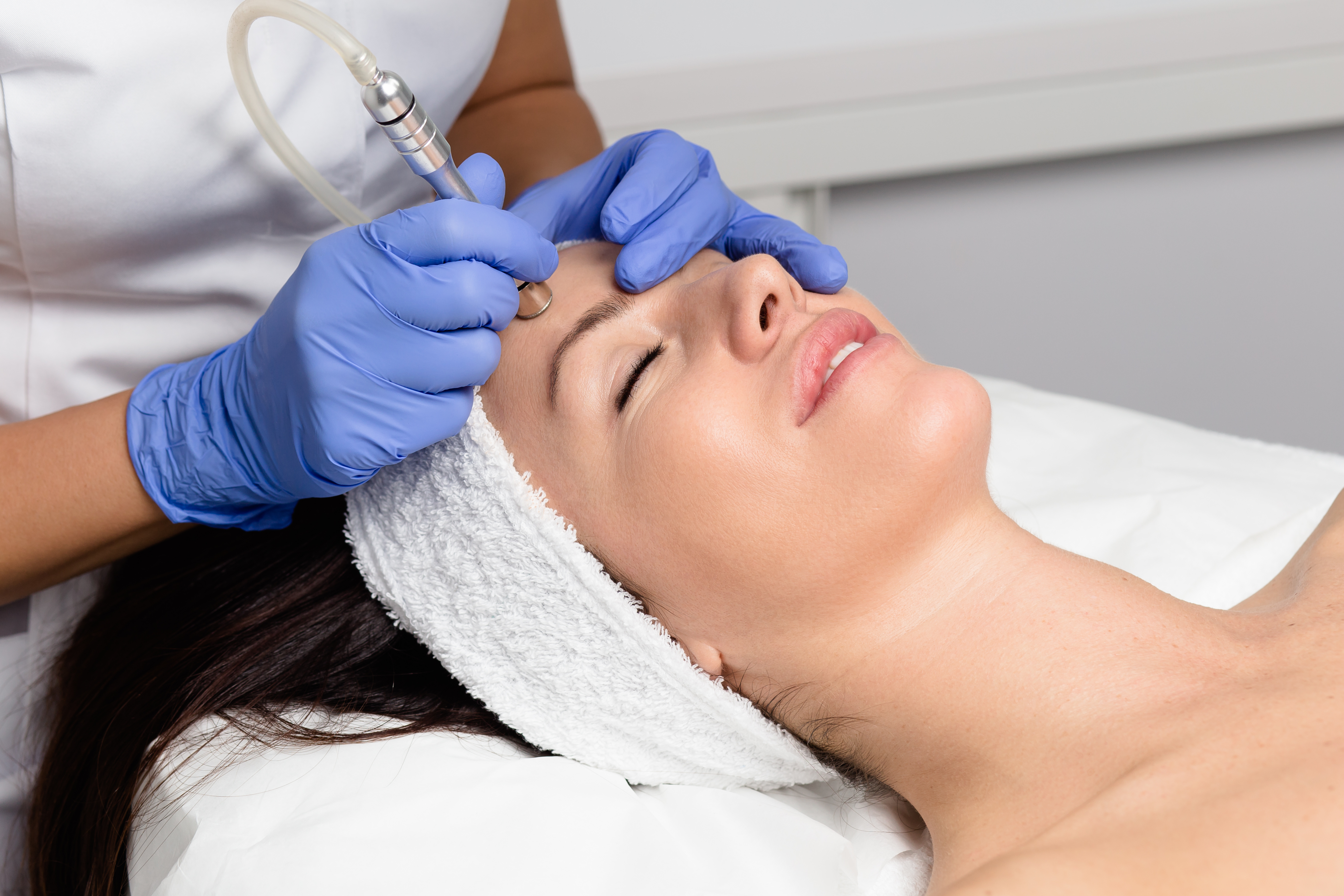 A woman getting facial microdermabrasion peeling treatment.