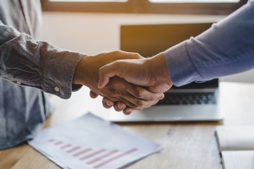 Two men shaking hands over a computer
