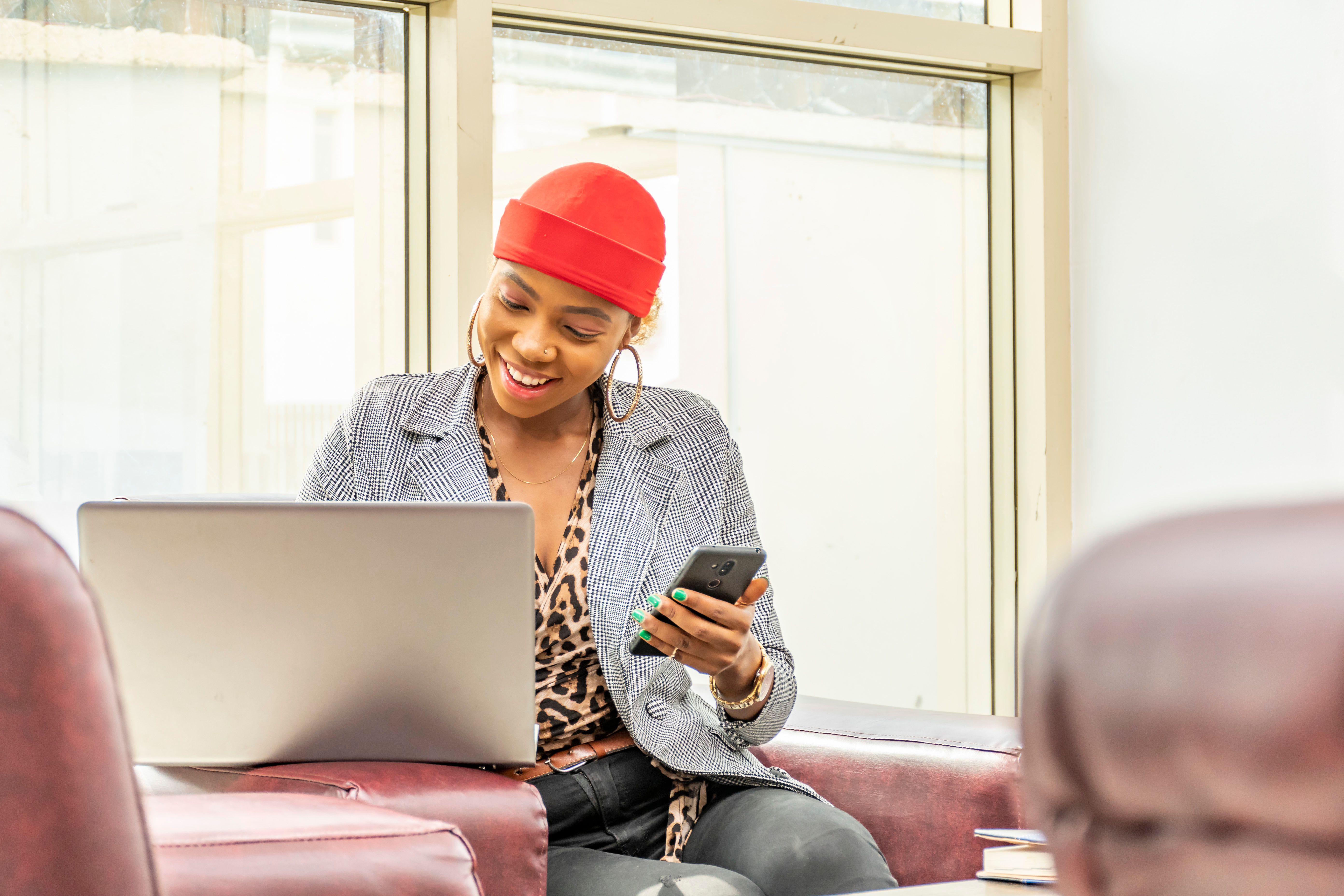 Younger woman looking at a computer while holding a cell phone