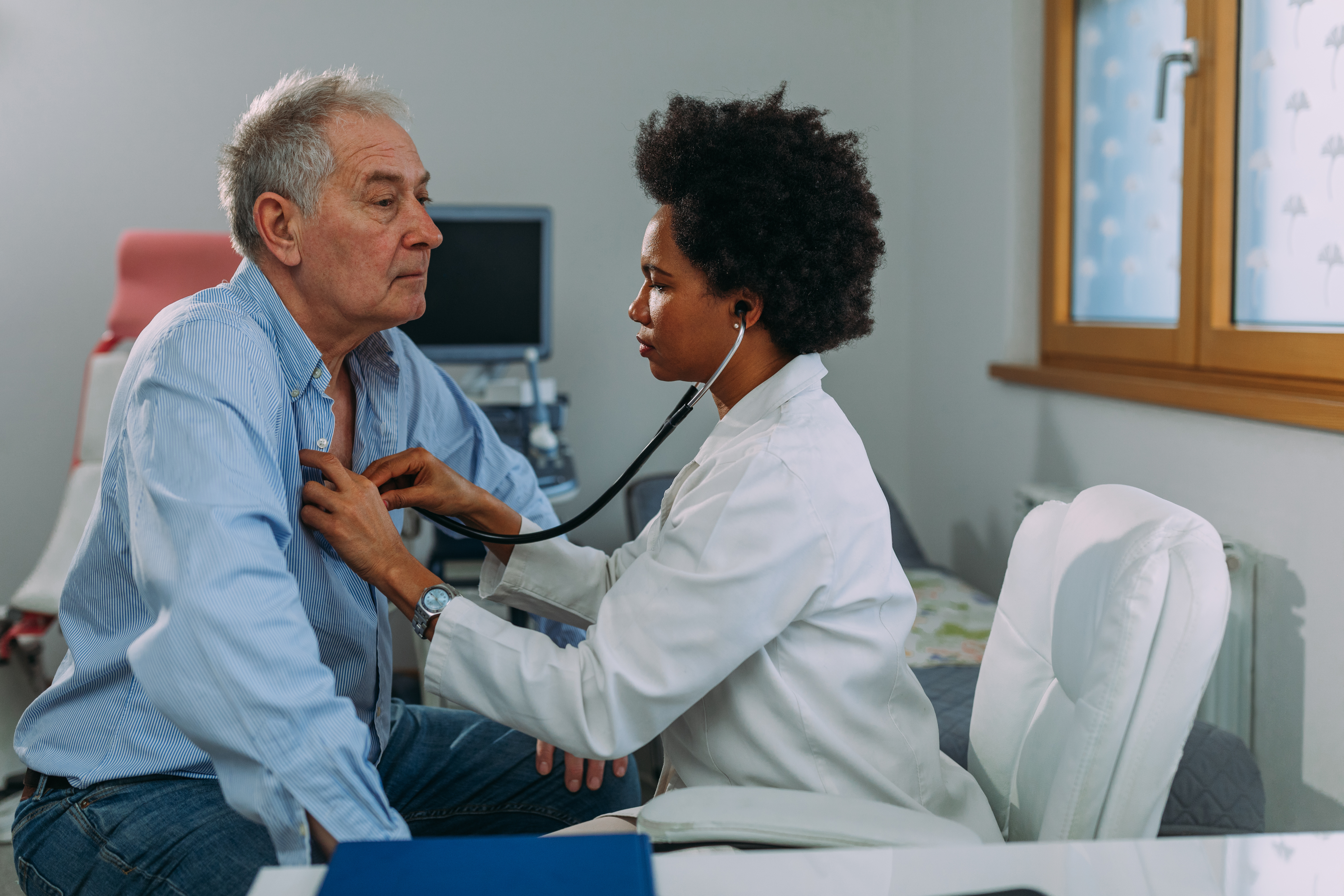 Older man getting checkup, heart checked, by female doctor