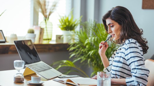 Woman looking at her notebook in front of a computer