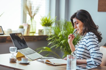 Woman looking at her notebook in front of a computer
