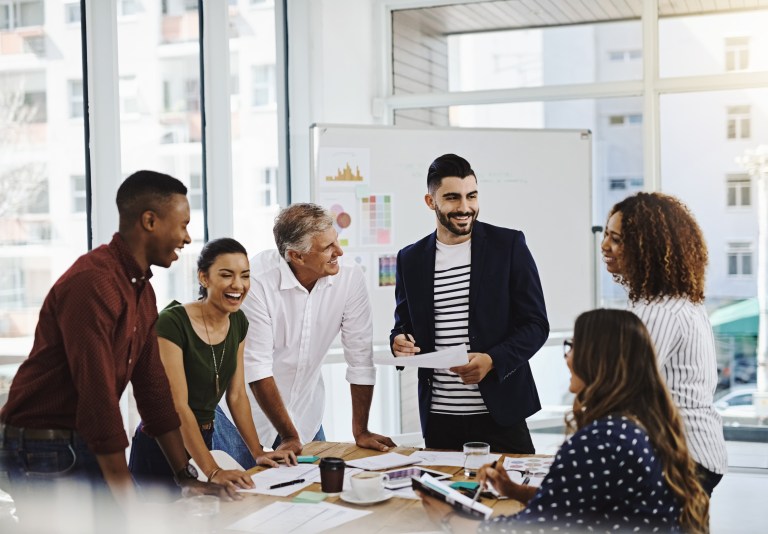 Group of employees in office, different ages, laughing and smiling