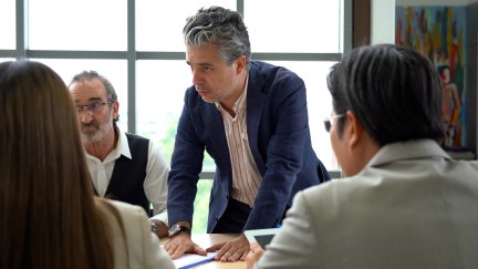 Male employee standing, managing, talking to table of employees