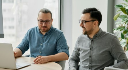 Two male employees talking, one with laptop