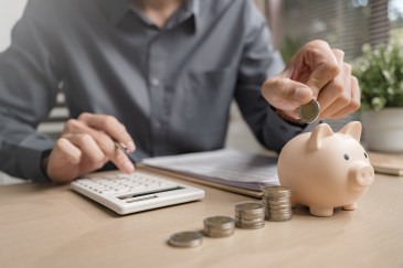 Man putting coins into piggy bank; saving