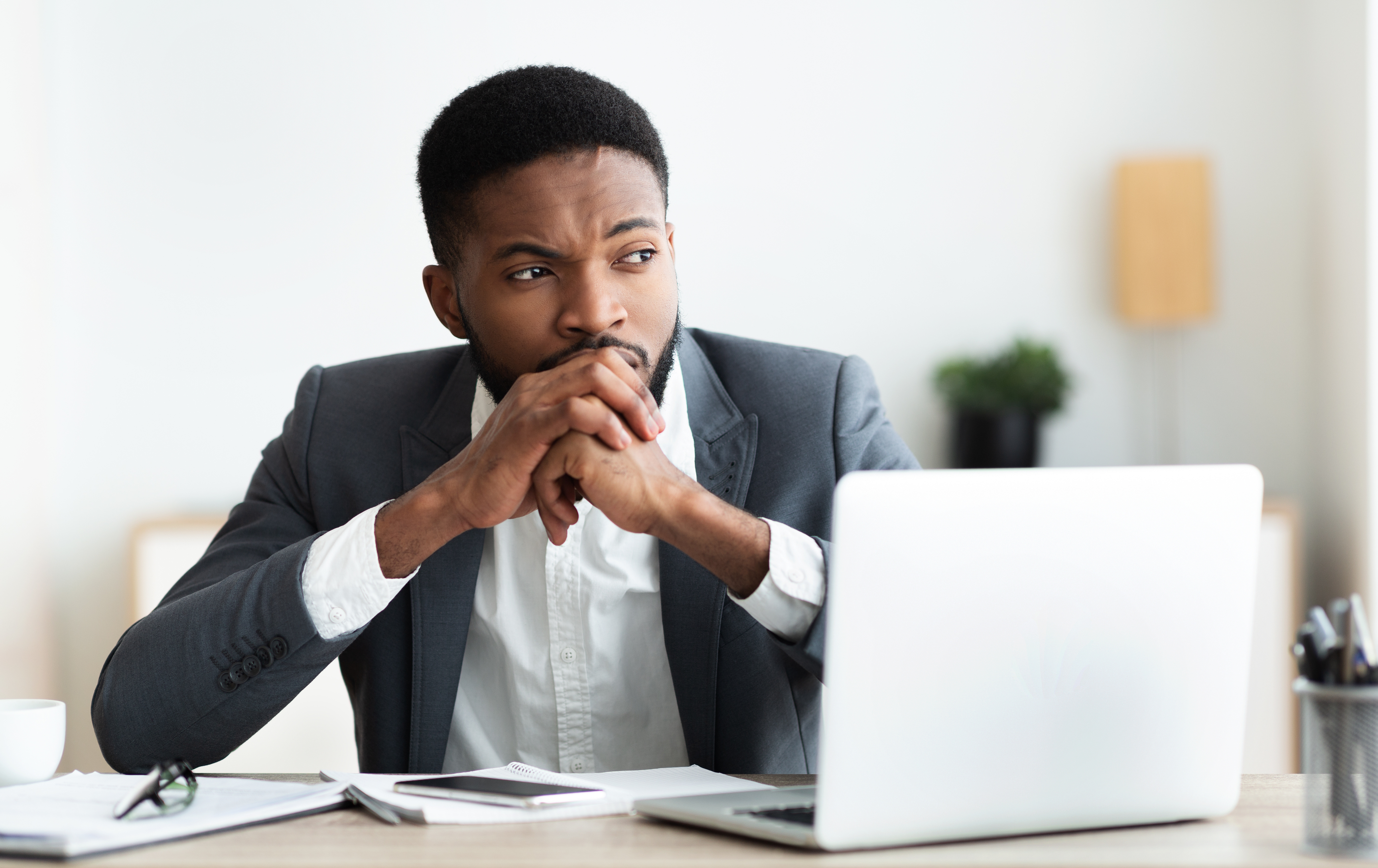 Employee sitting at desk with laptop, thinking
