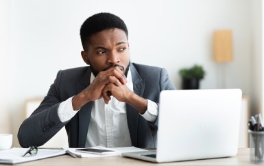 Employee sitting at desk with laptop, thinking