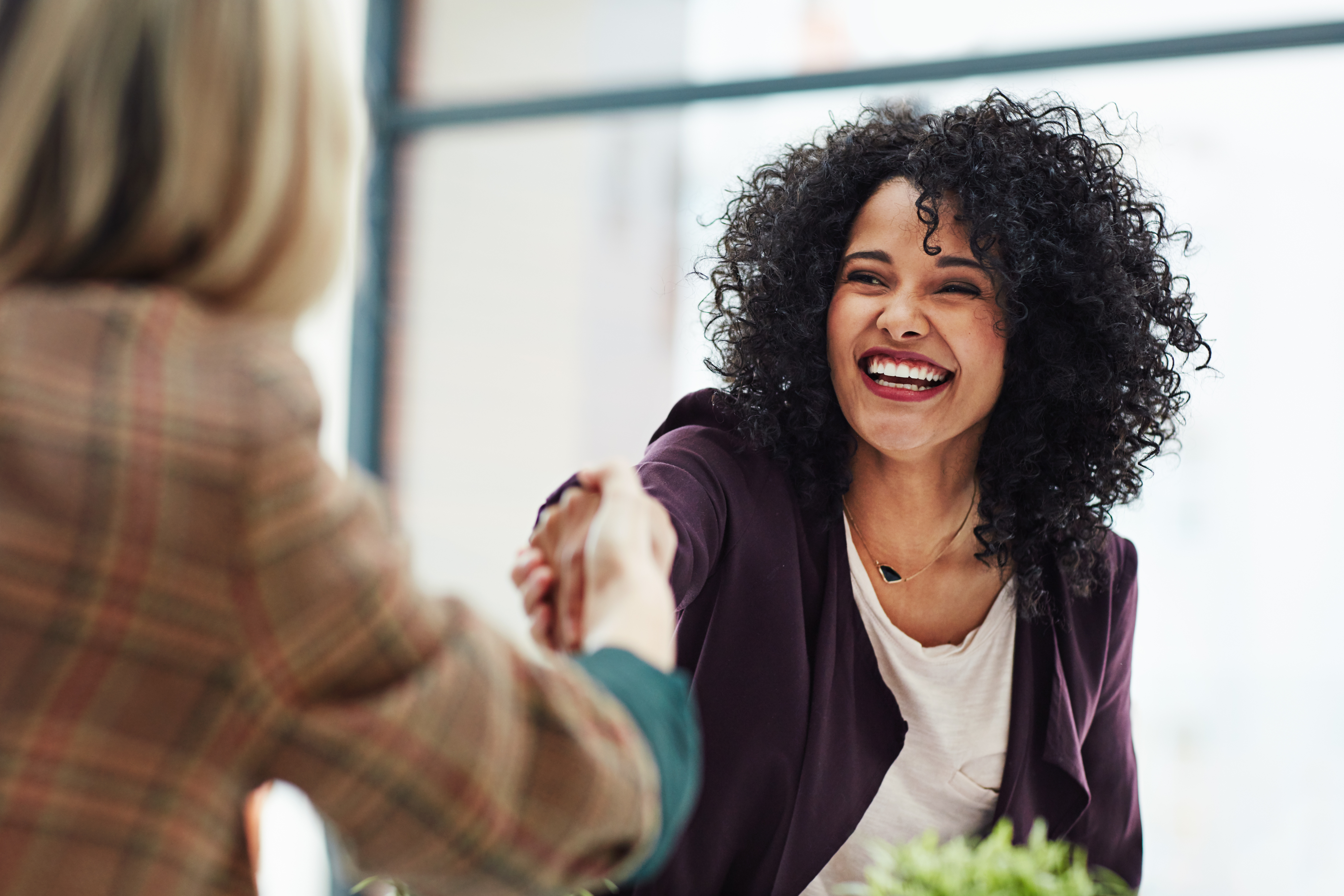 Woman smiling, shaking hand of boss