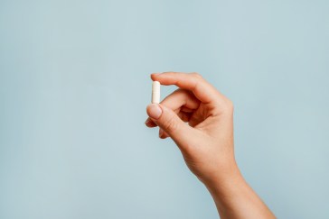 Hand holding pill between two fingers