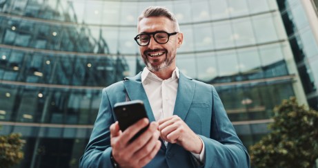 Man in suit holding cellphone outside of office building