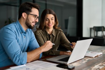 Two employees, man and woman, working, looking at computer