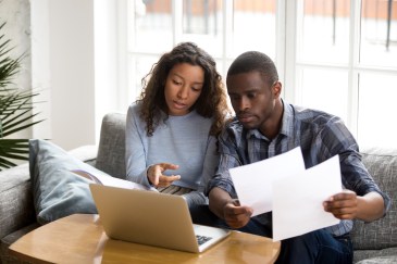 Couple looking at bills and laptop computer