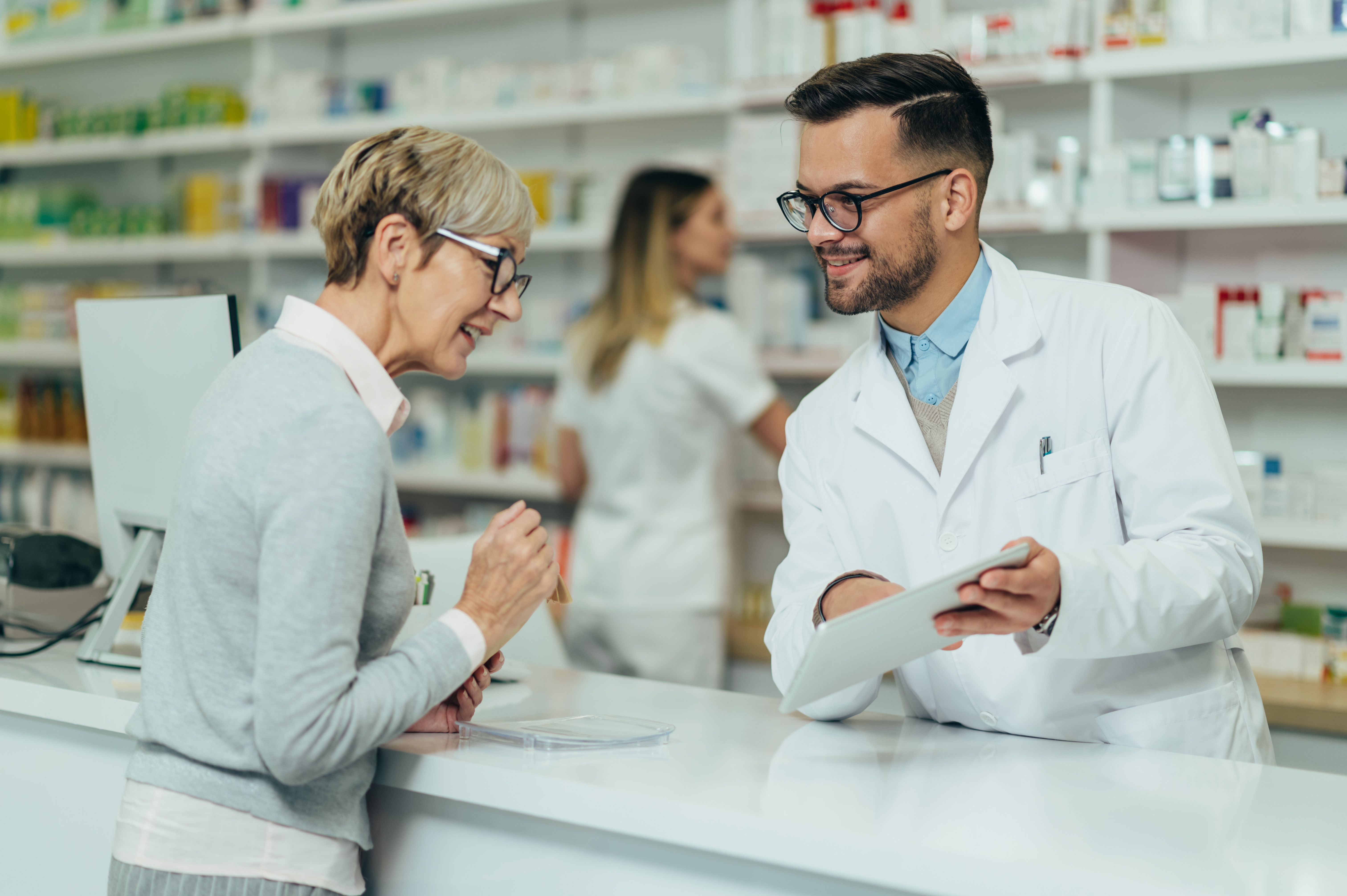 Woman speaking with pharmacist, looking at paper