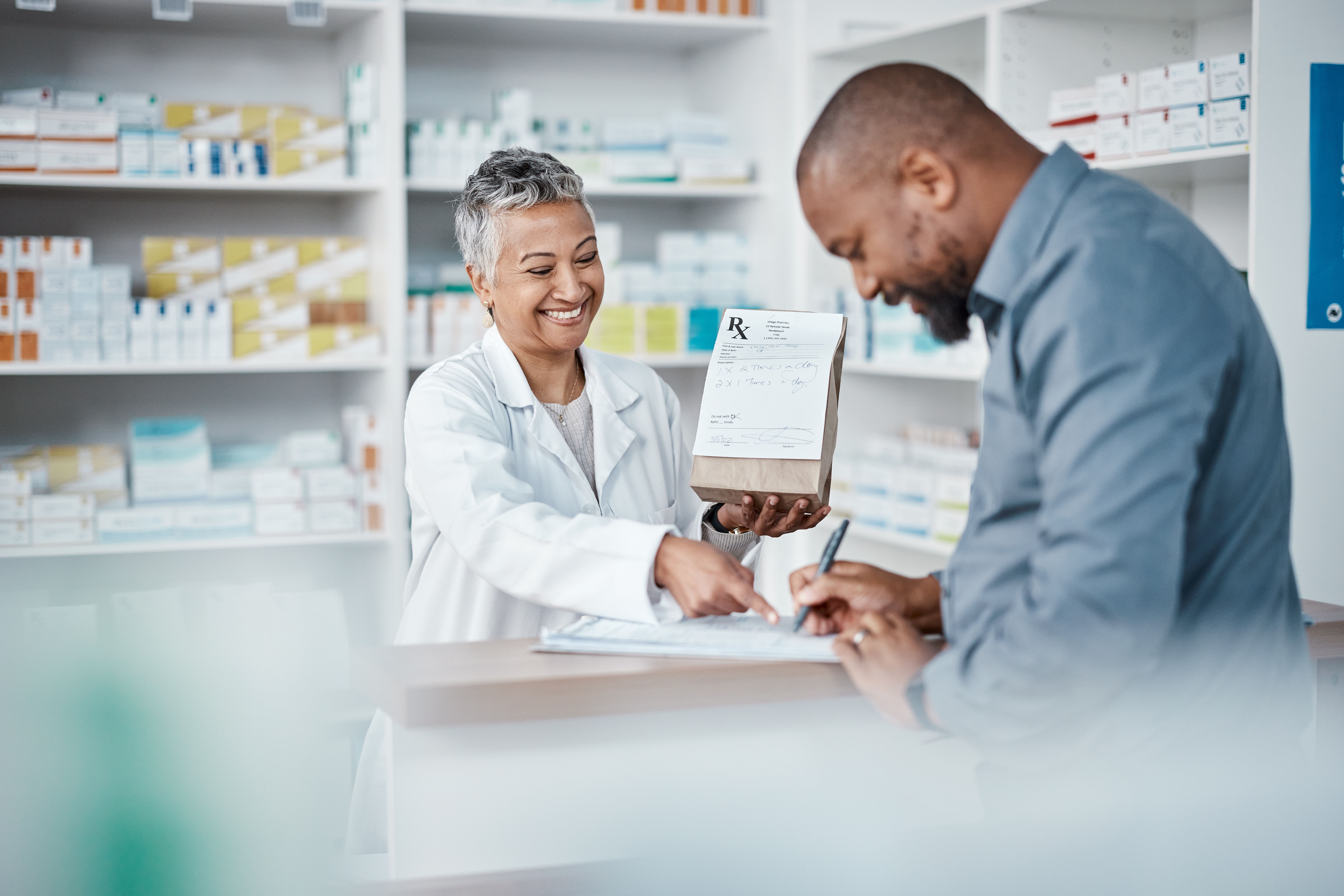 Man at pharmacy counter with pharmacist, smiling