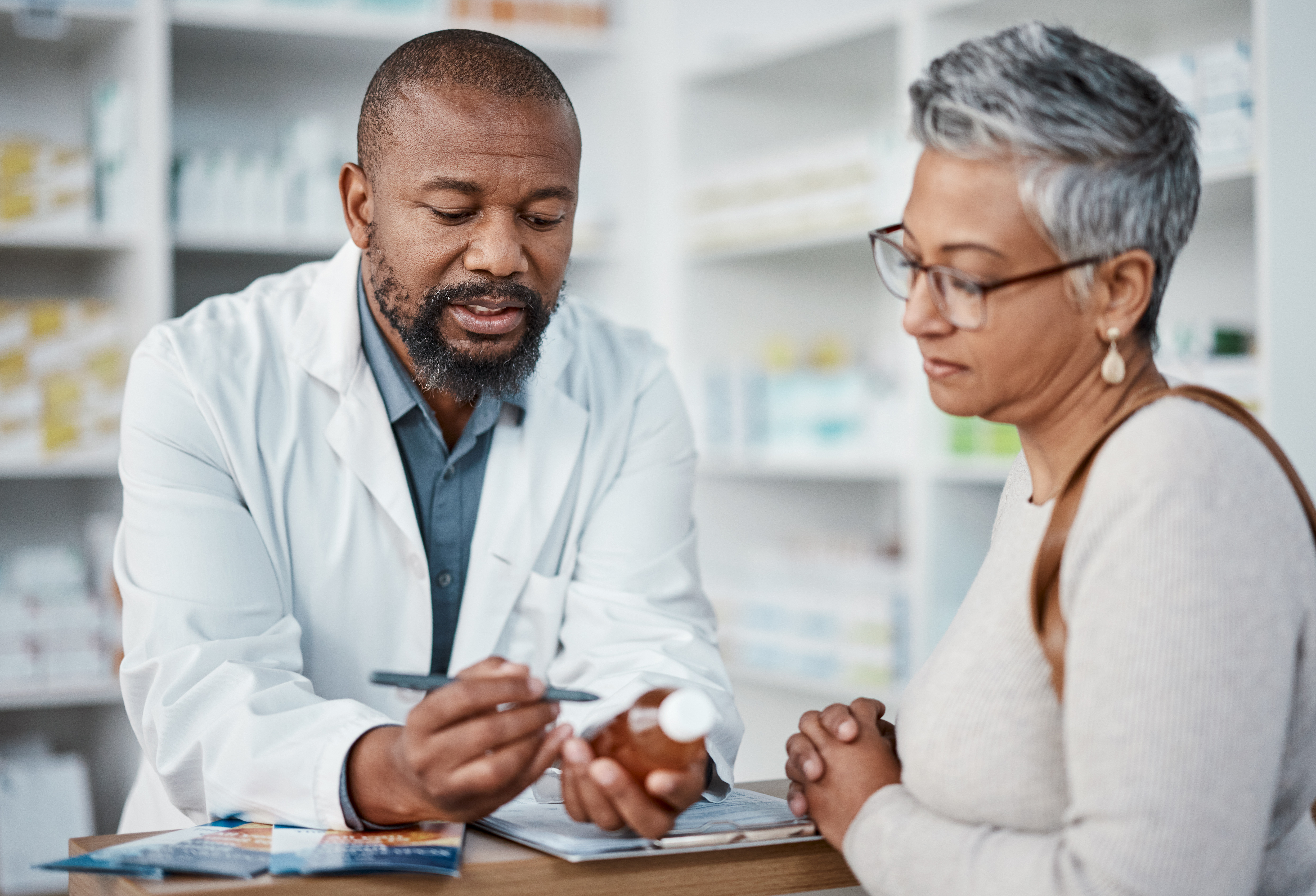 Male pharmacist discussing medication with female patient