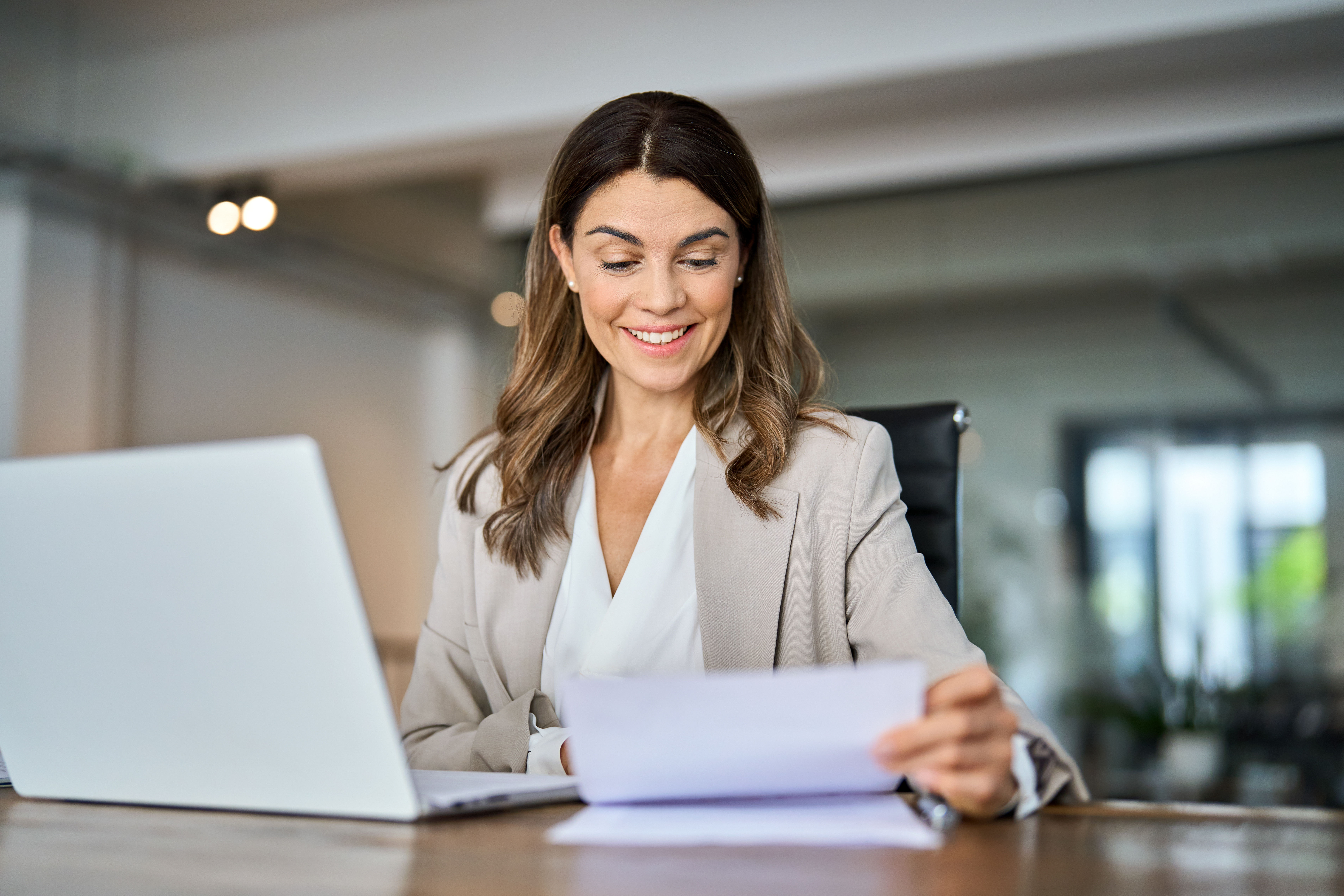 Woman sitting at desk looking at paper