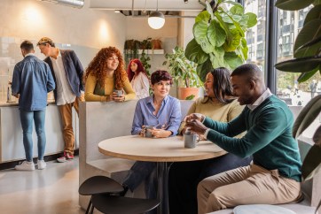 Employees talking, sitting together in break room, drinking coffee, socializing