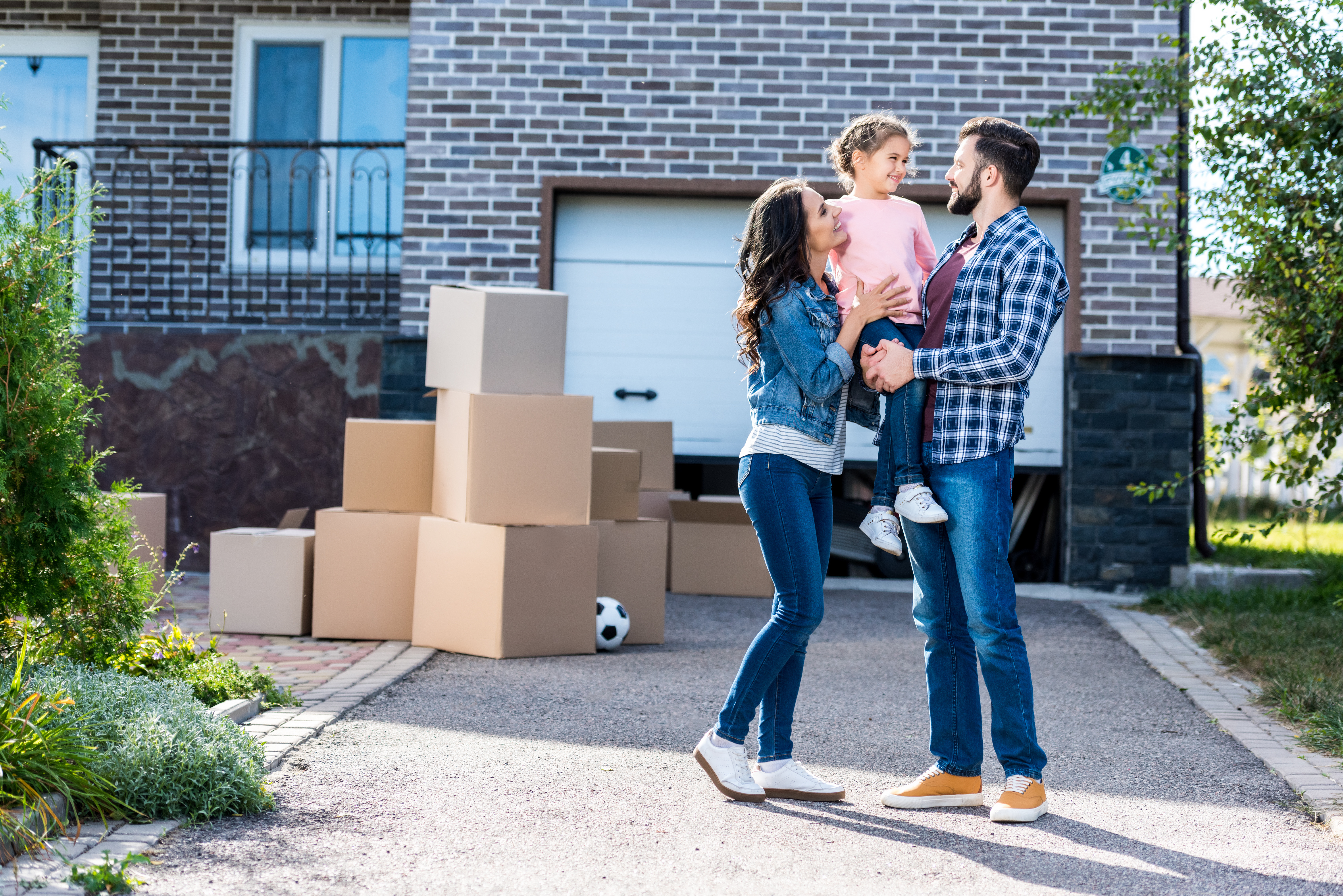 Family with small child moving into home, boxes on driveway
