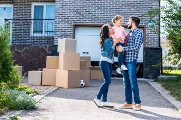 Family with small child moving into home, boxes on driveway