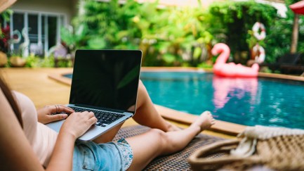 Woman sitting by the pool with a computer
