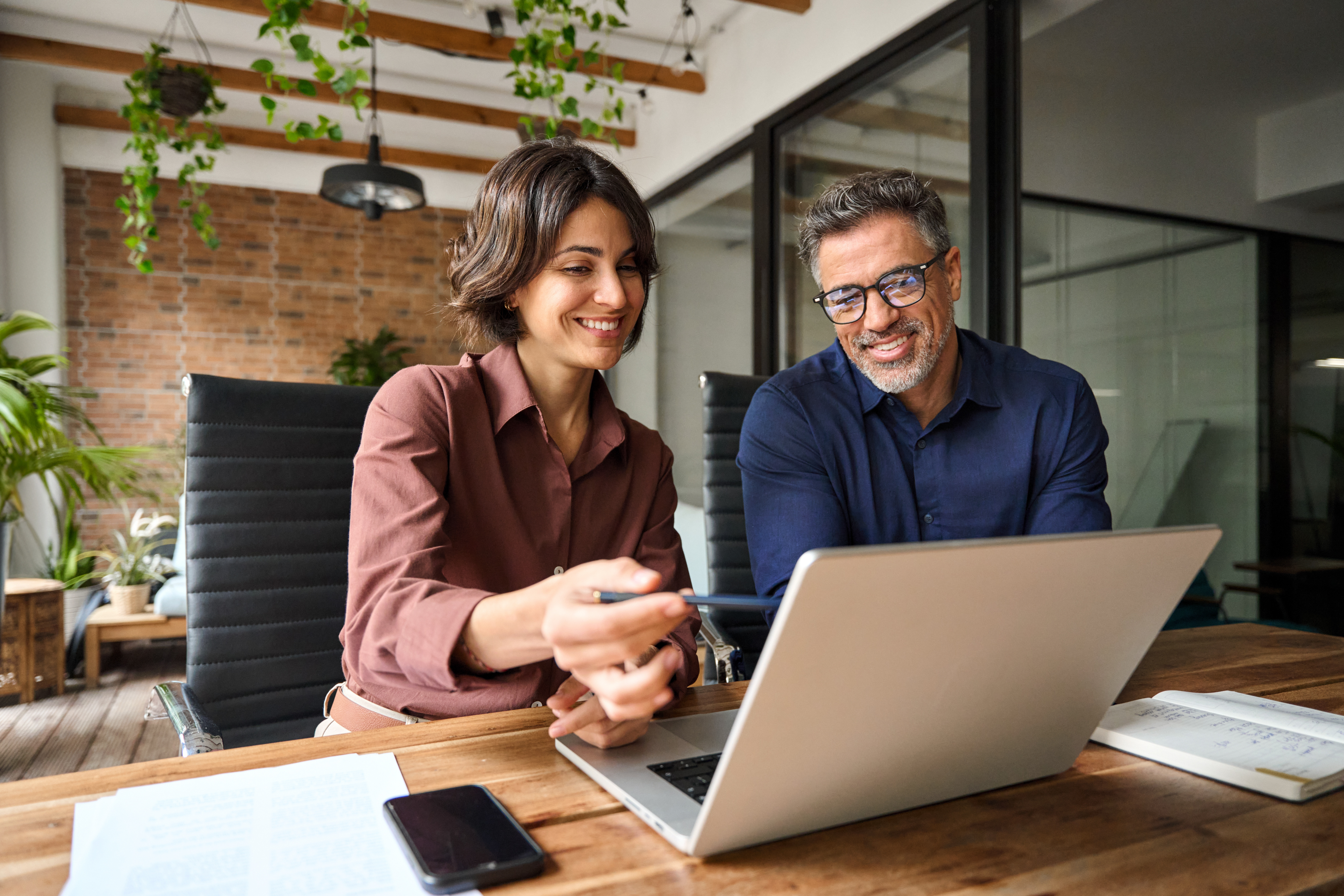Two people talking at desk, looking at computer