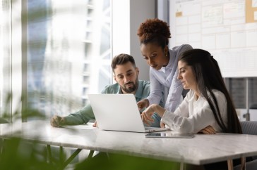 Group of three employees looking at computer