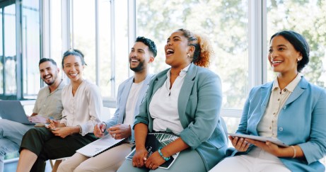 Line of employees sitting, laughing, smiling