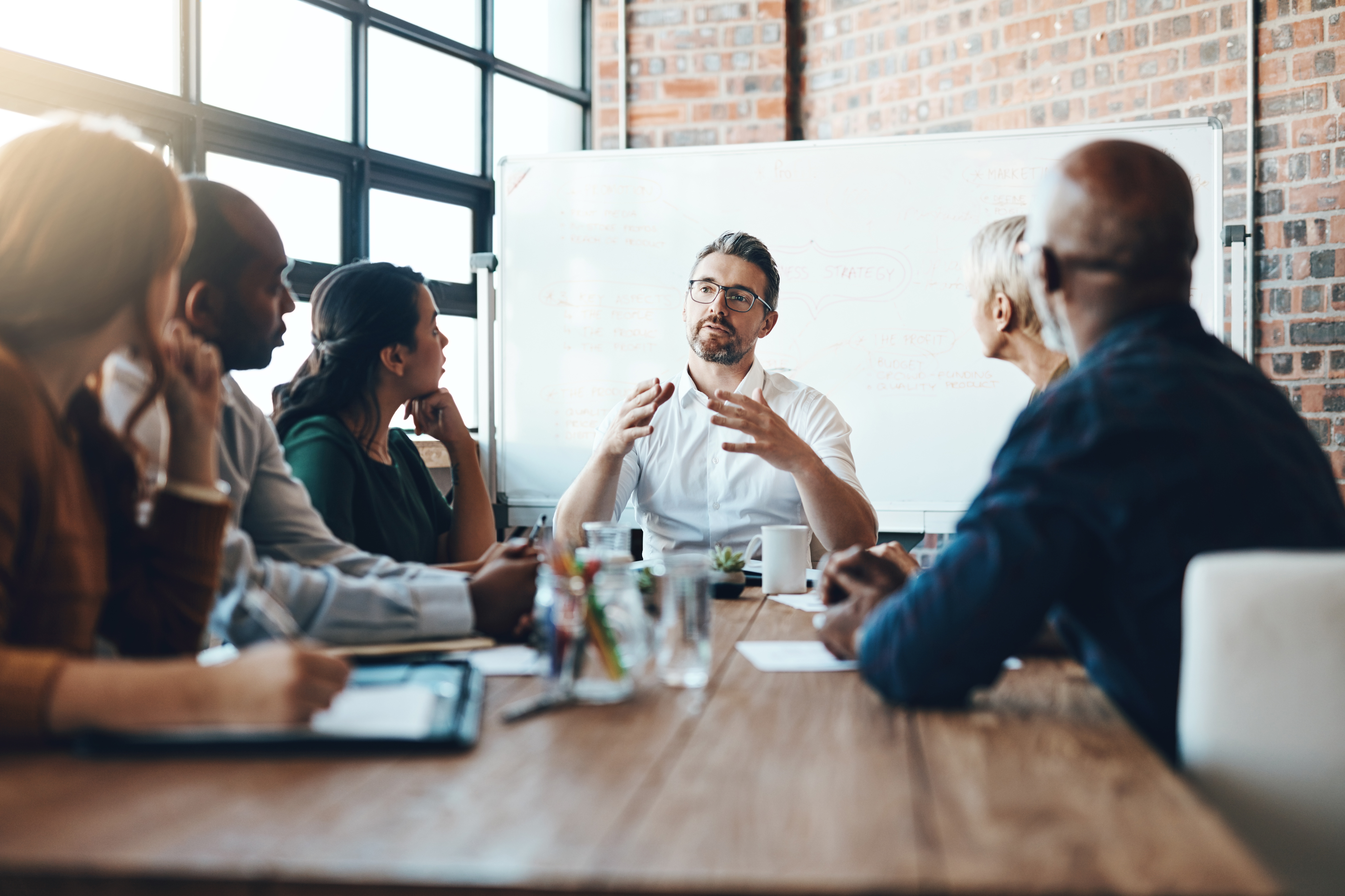Man sitting at head of conference table, talking with other employees