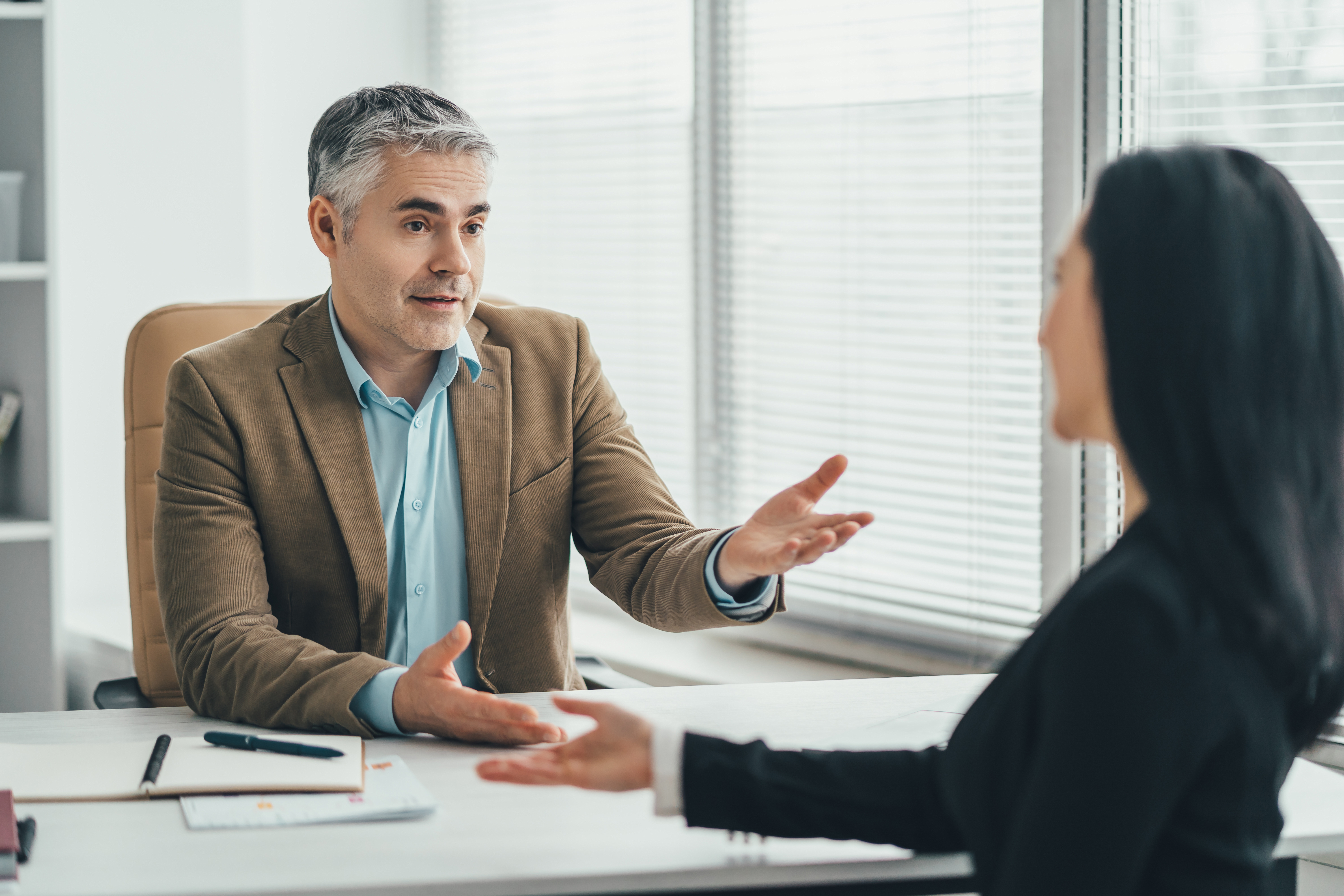 Two employees talking across desk