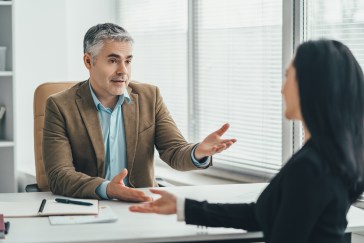 Two employees talking across desk