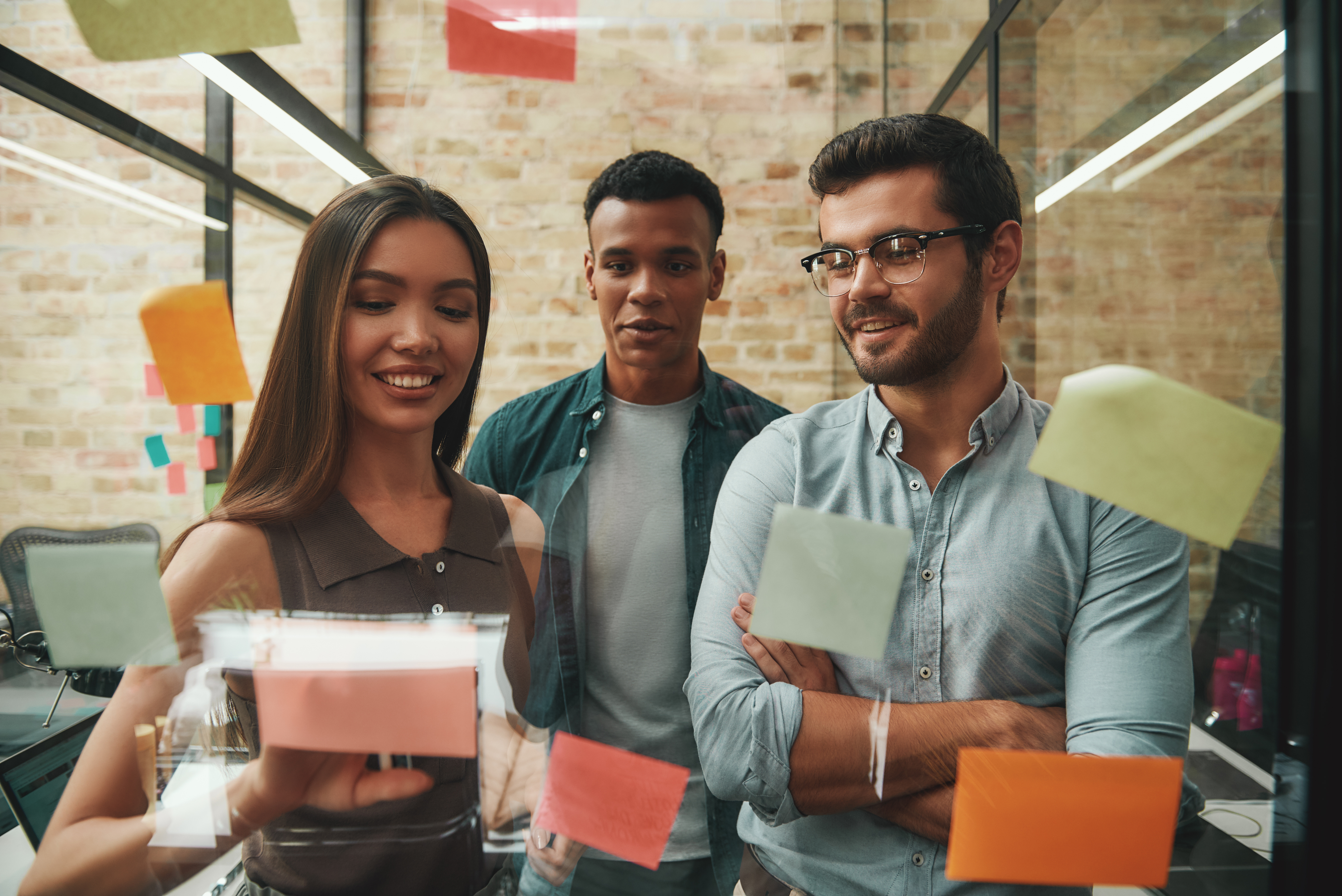 Employees working with post-its on glass wall
