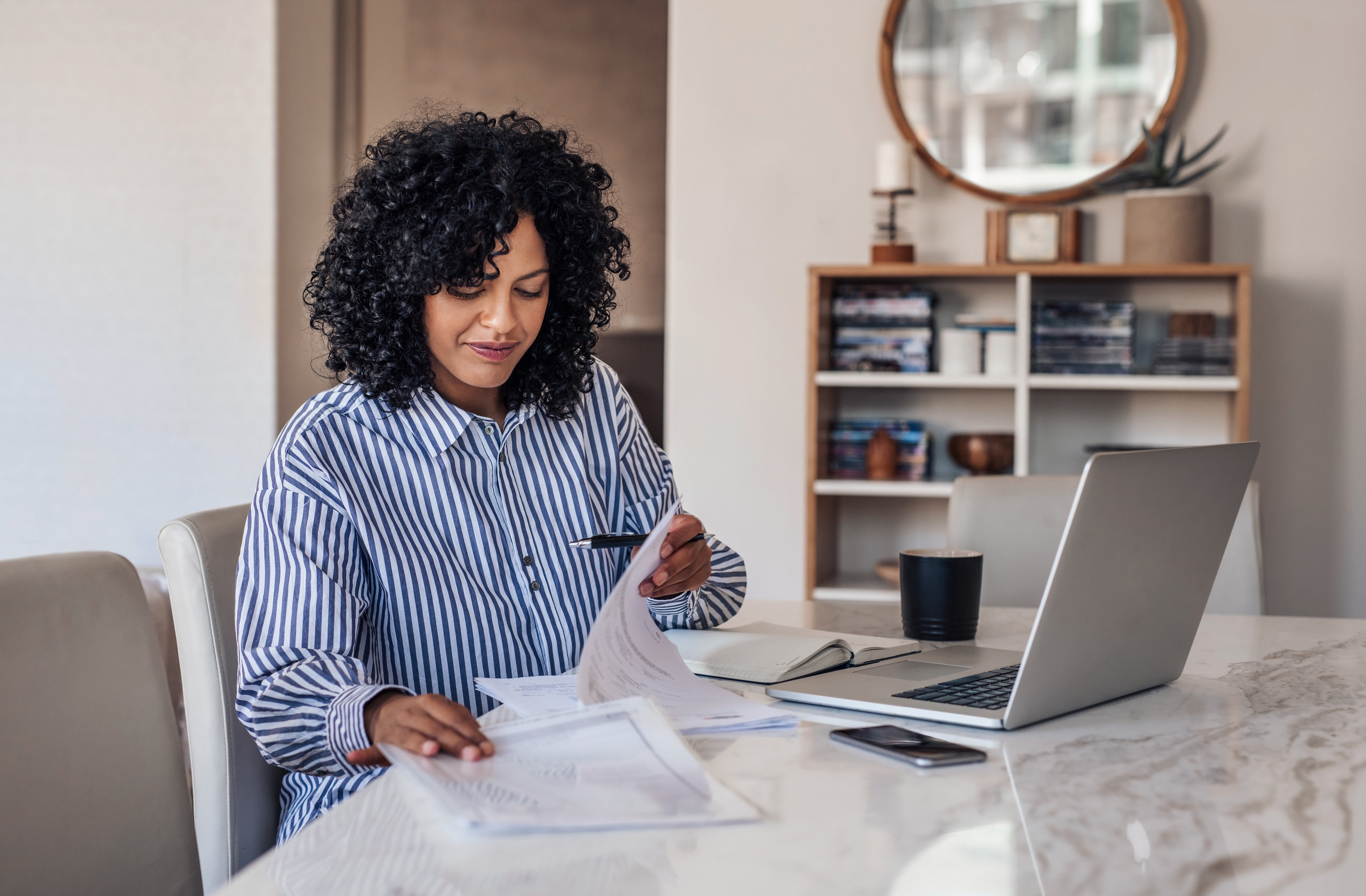 Woman looking through multiple piles of paperwork