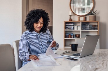 Woman looking through multiple piles of paperwork