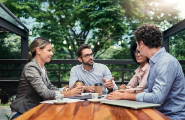 Group of professionals sitting outside at table, talking