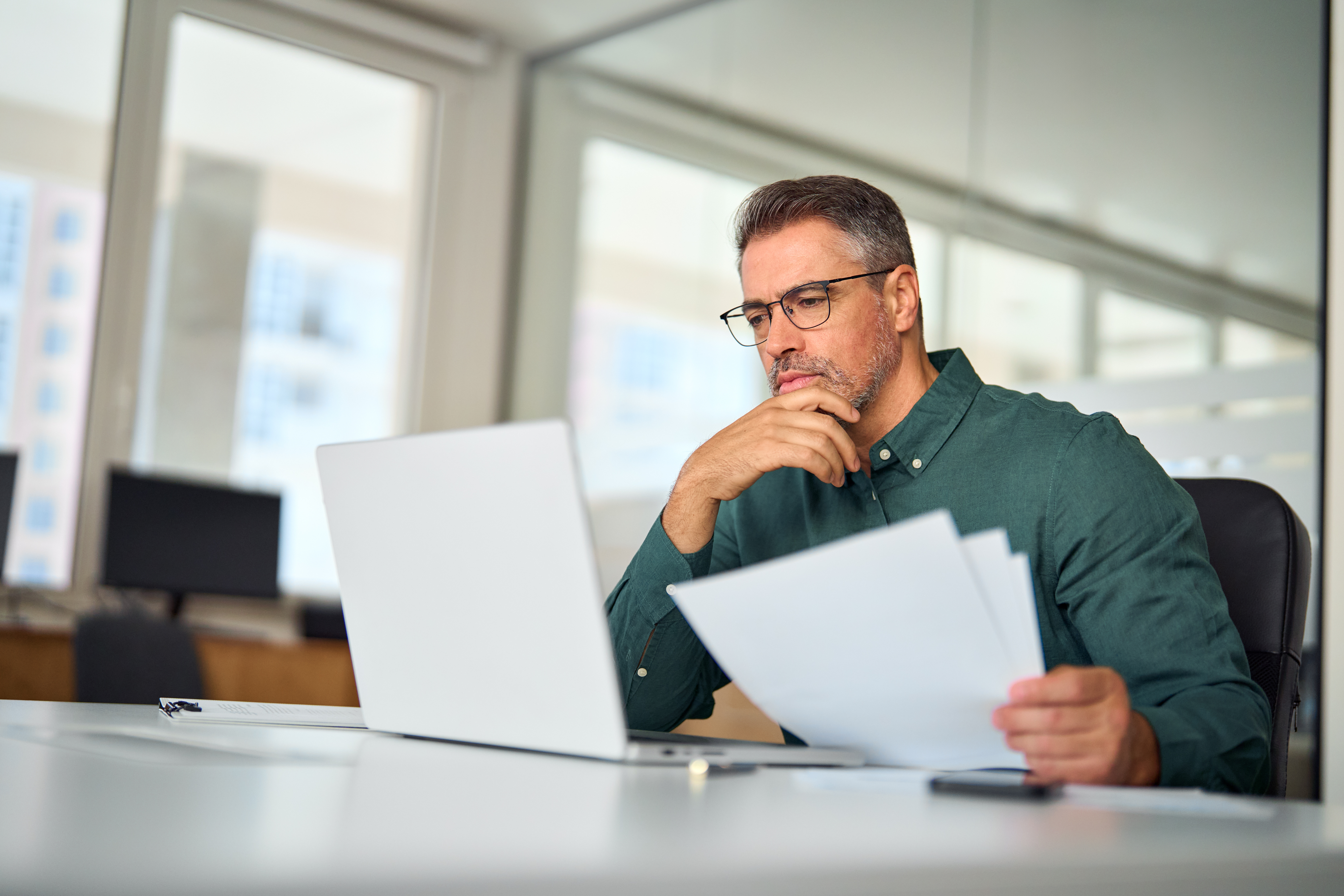 Man looking at paperwork and laptop computer