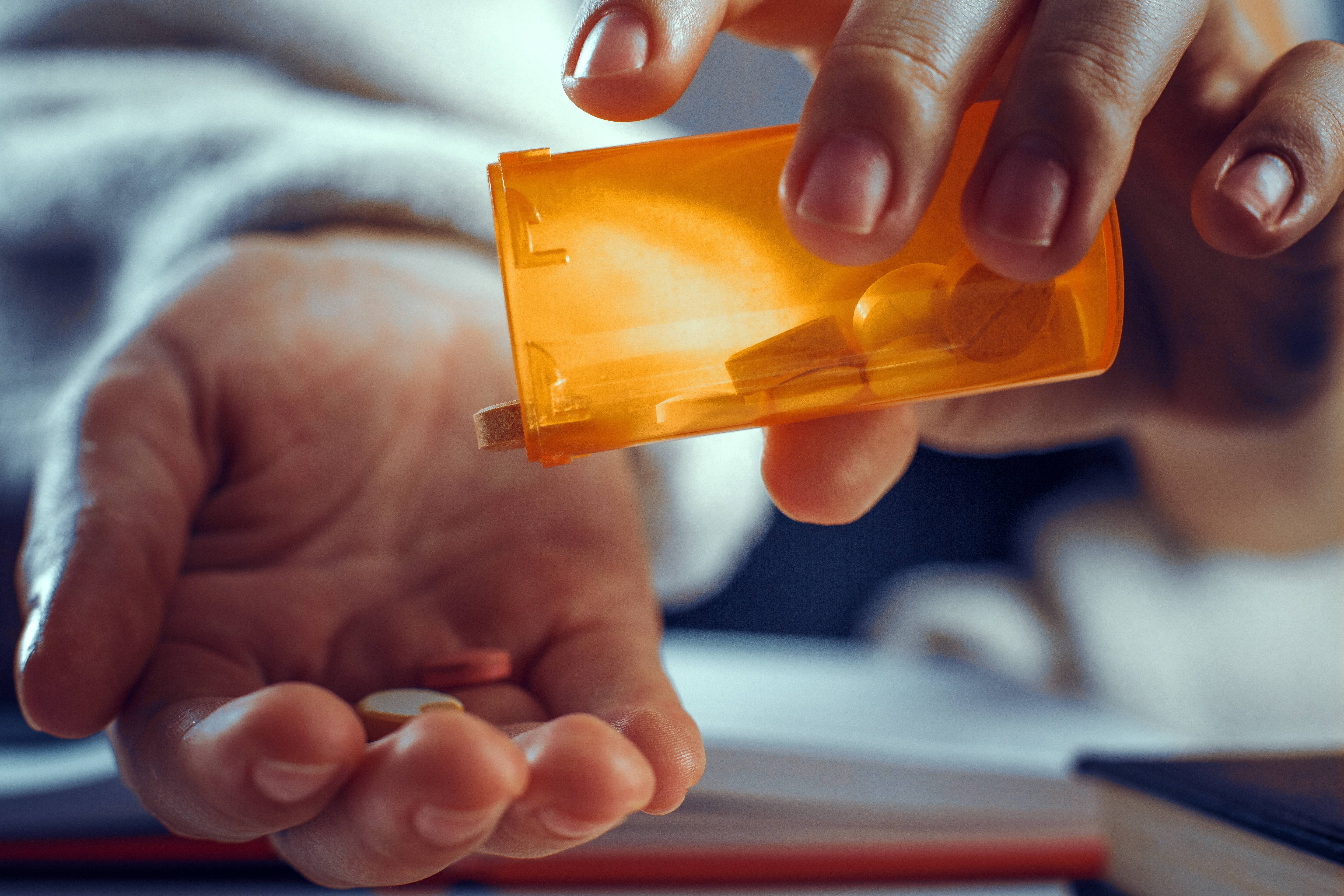 Person pouring prescription pills into hand