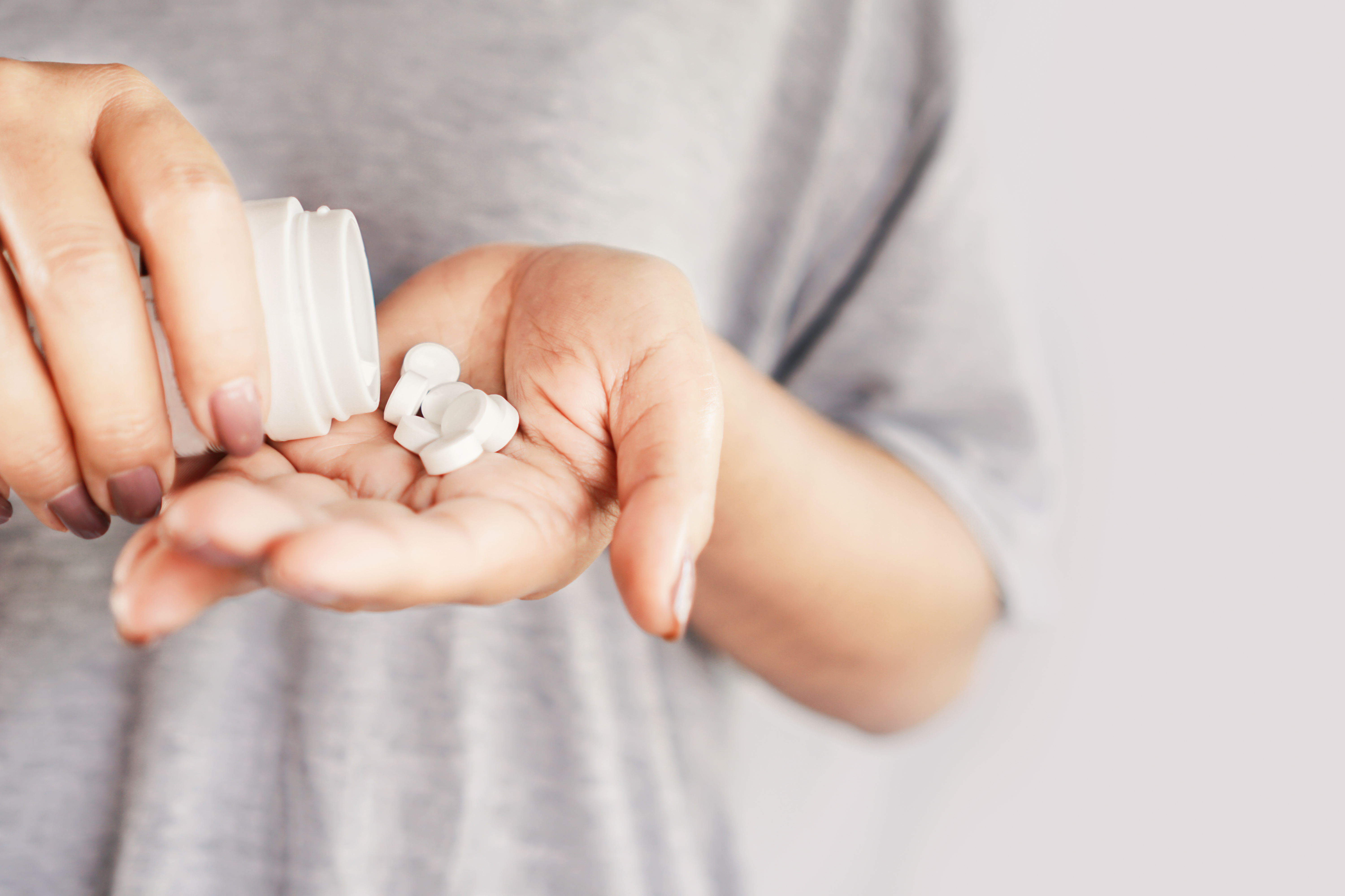 Woman pouring pills into palm of hand