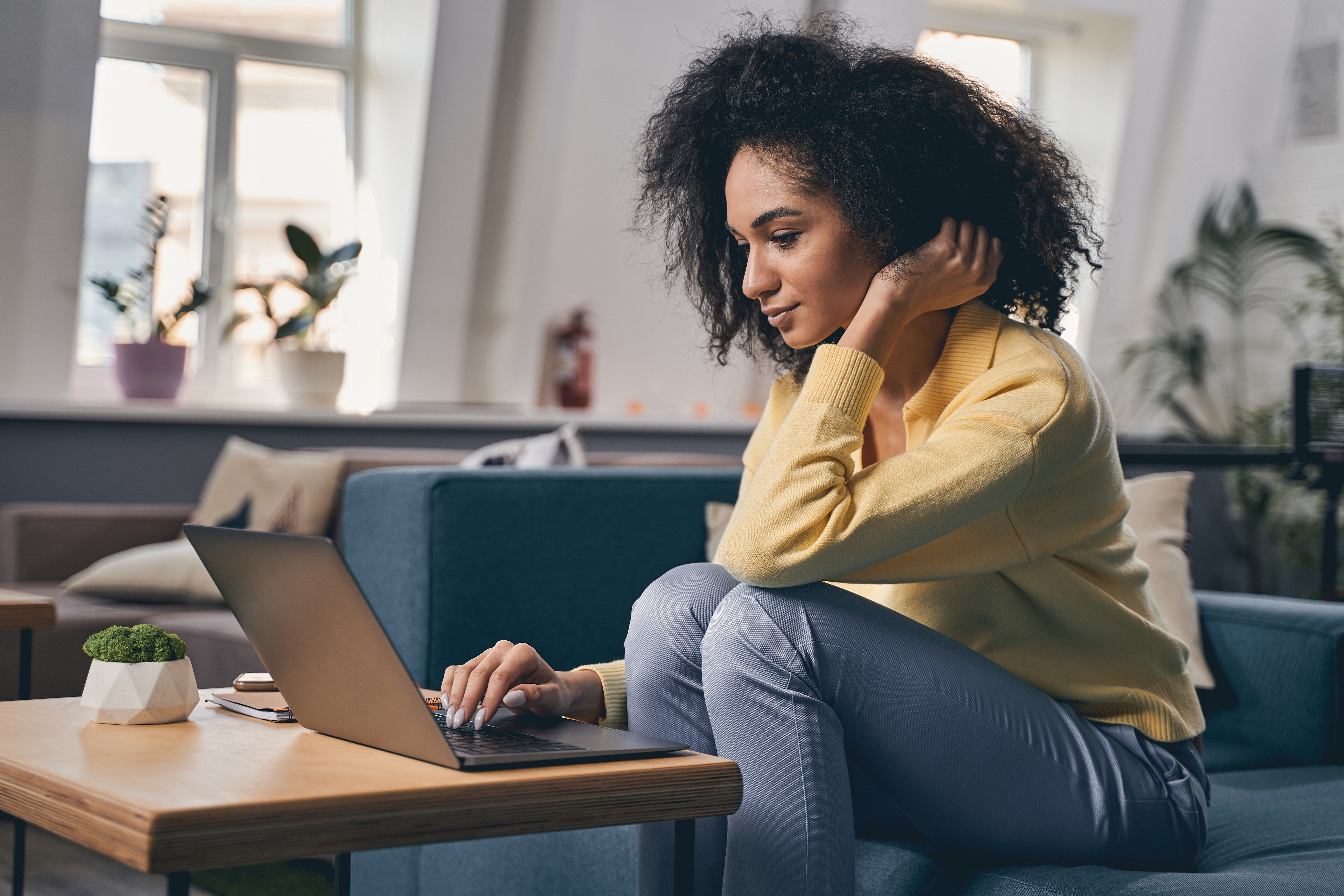 Woman working at a laptop, sitting on couch