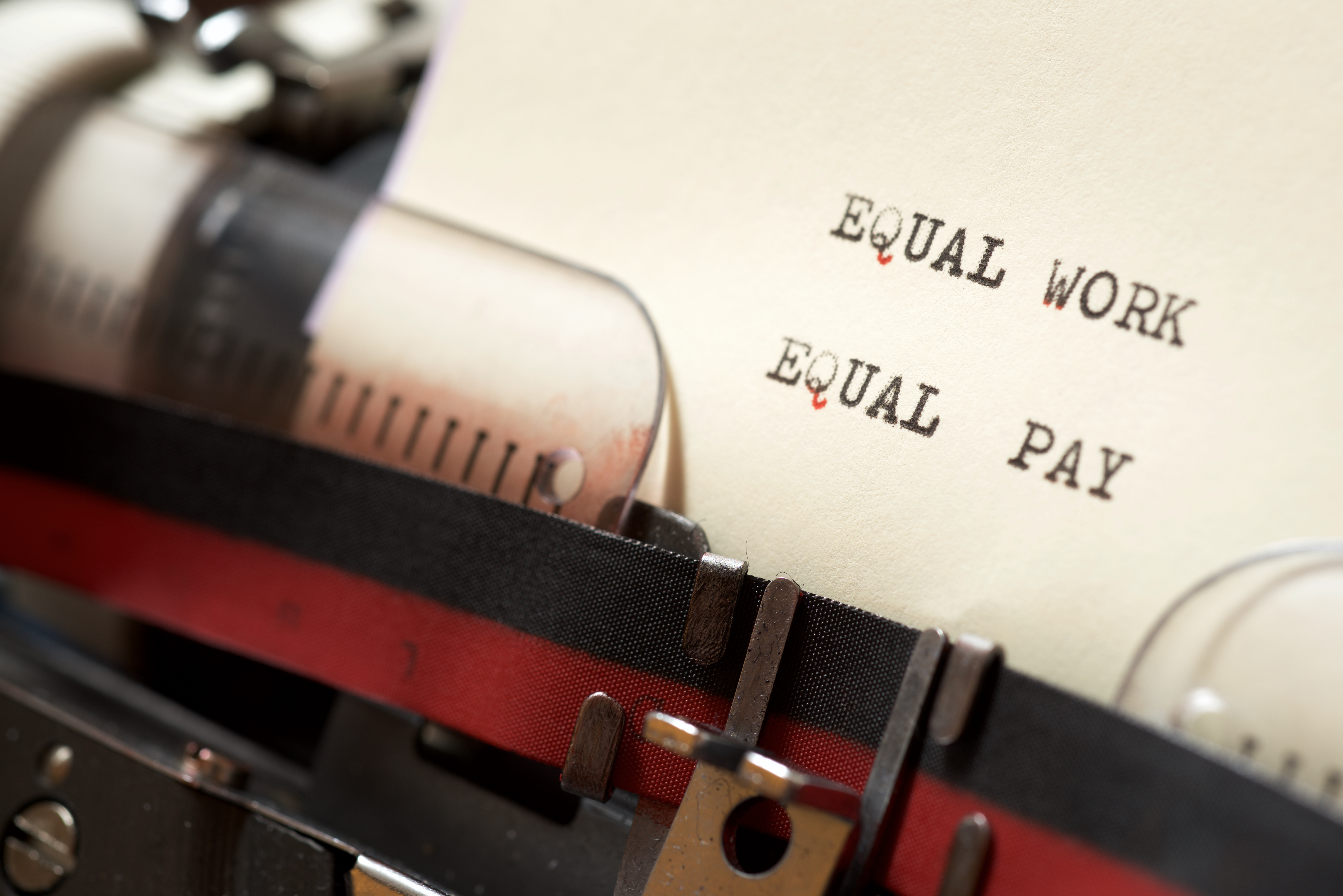 A typewriter with the words Equal Work and Equal Pay typed out on a sheet of paper.