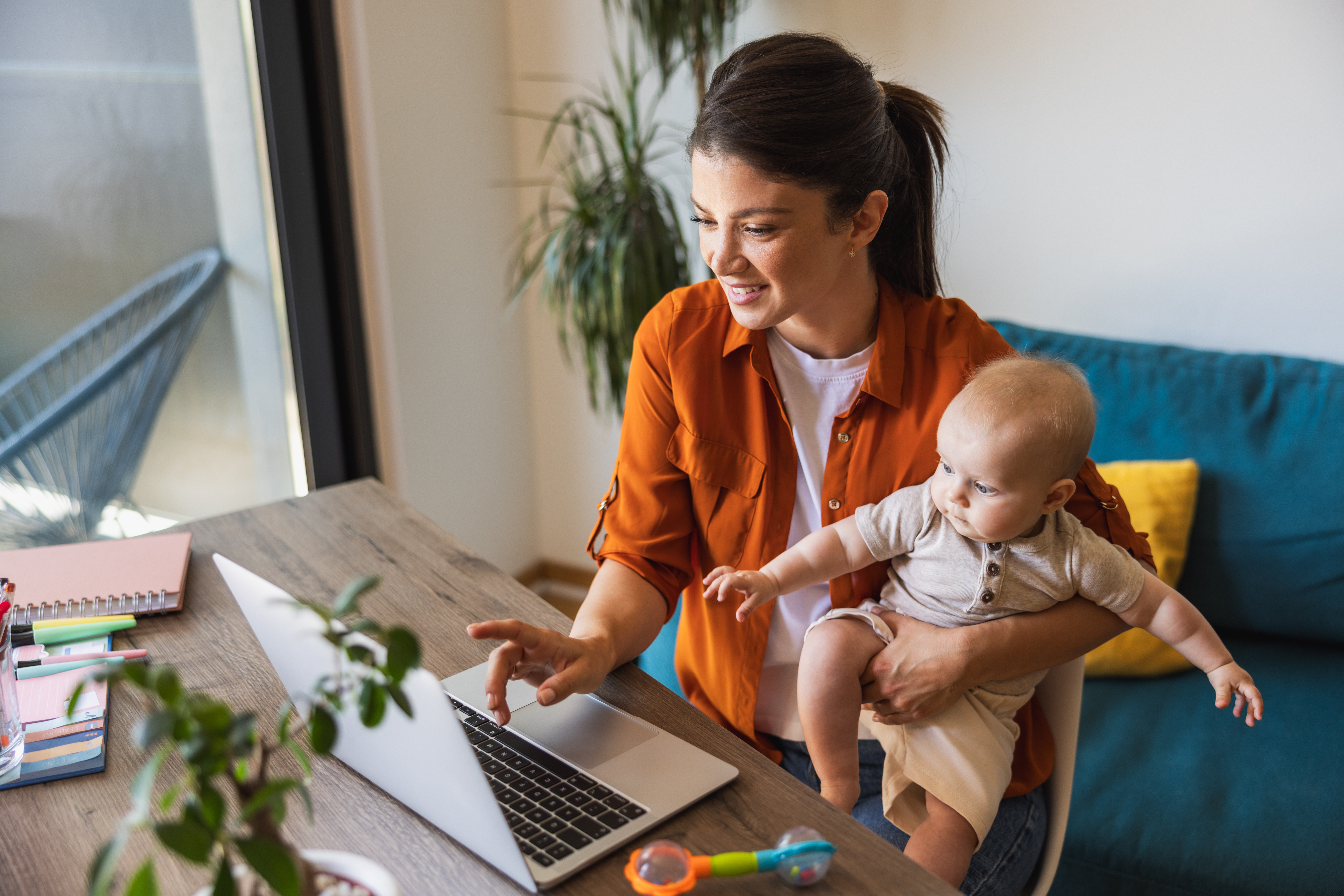 A woman sitting in front of a laptop with a baby.