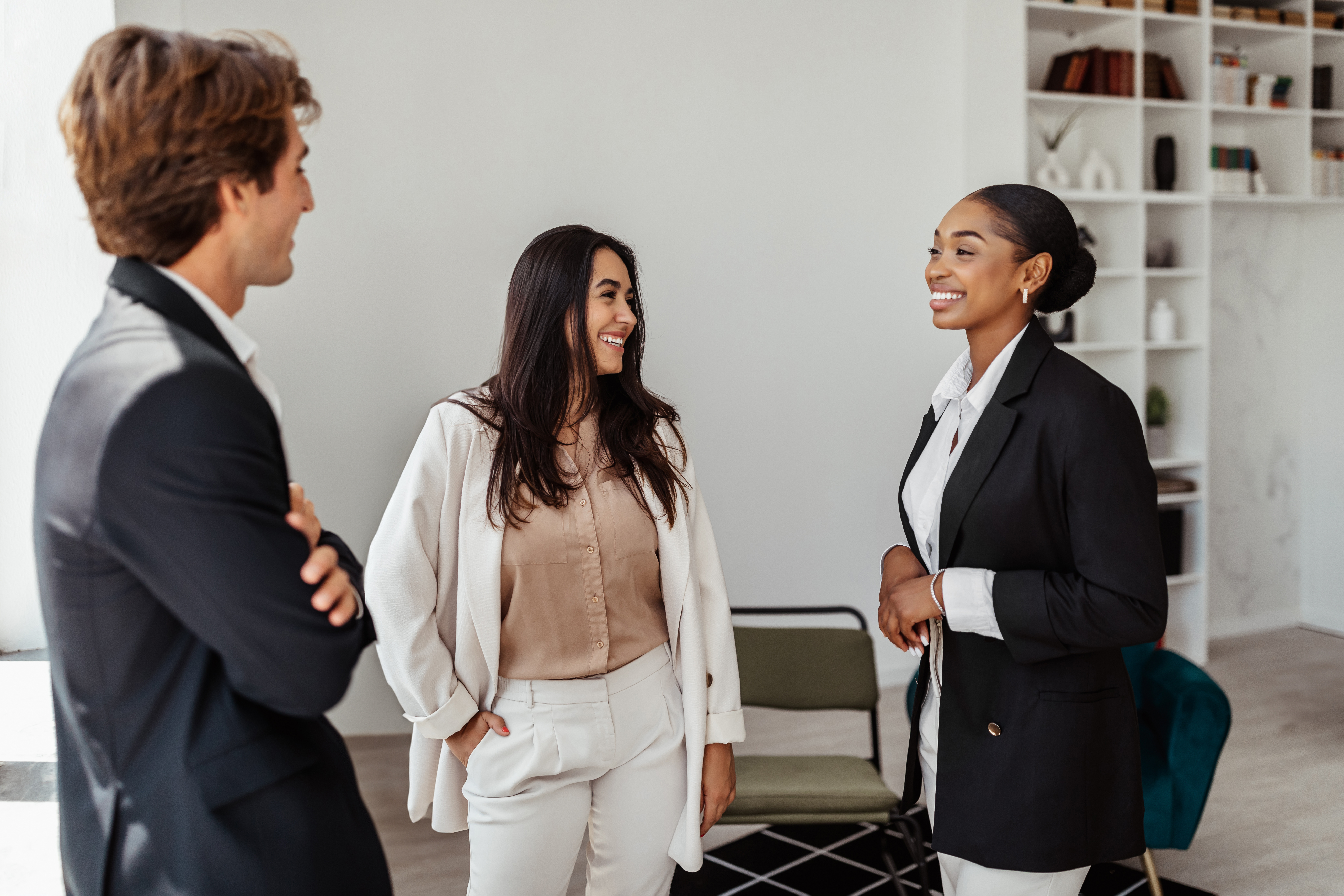 Three employees, standing, talking in office